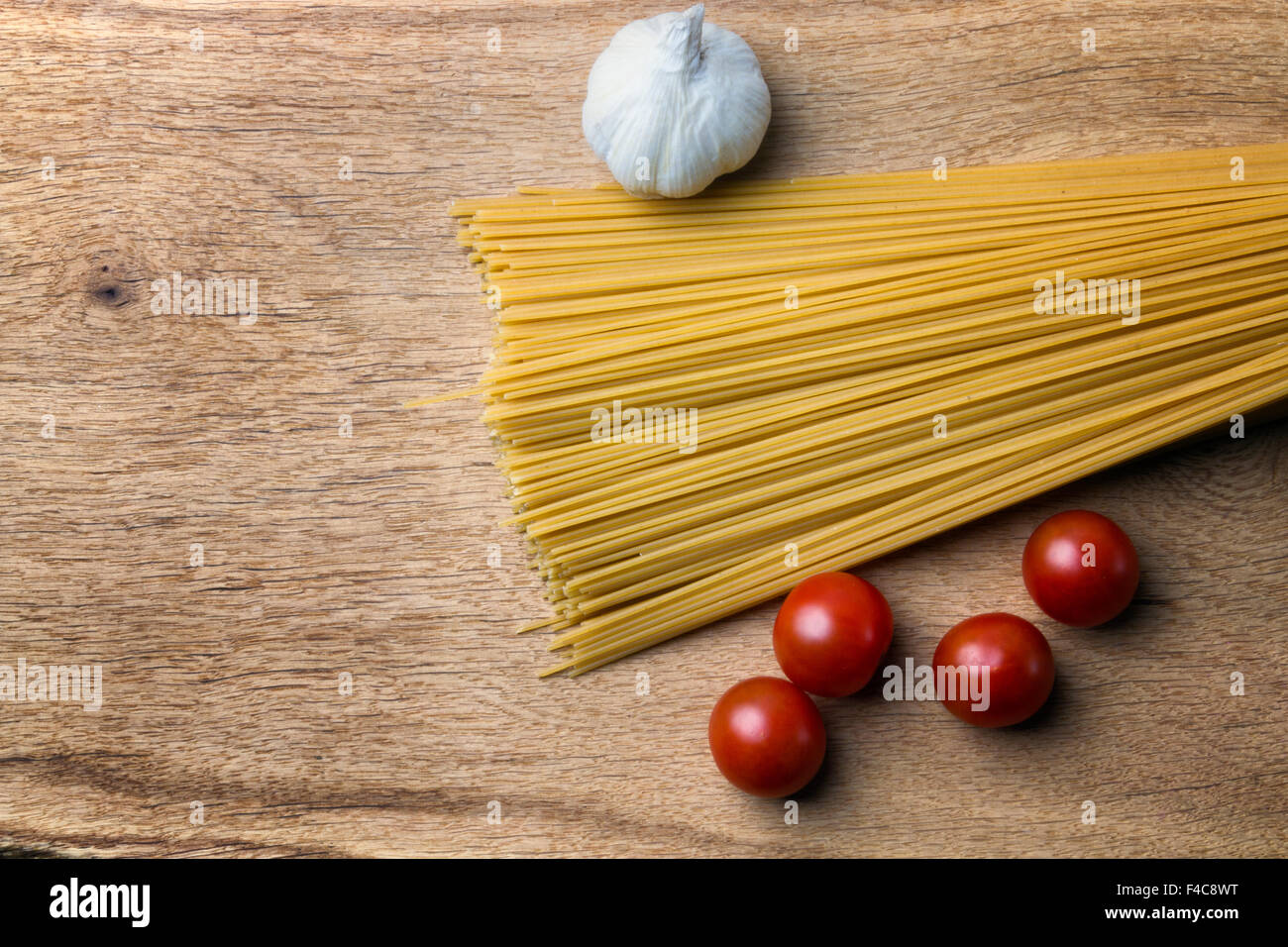 Aglio, i pomodorini cotte e di spaghetti su una tavola di legno Foto Stock