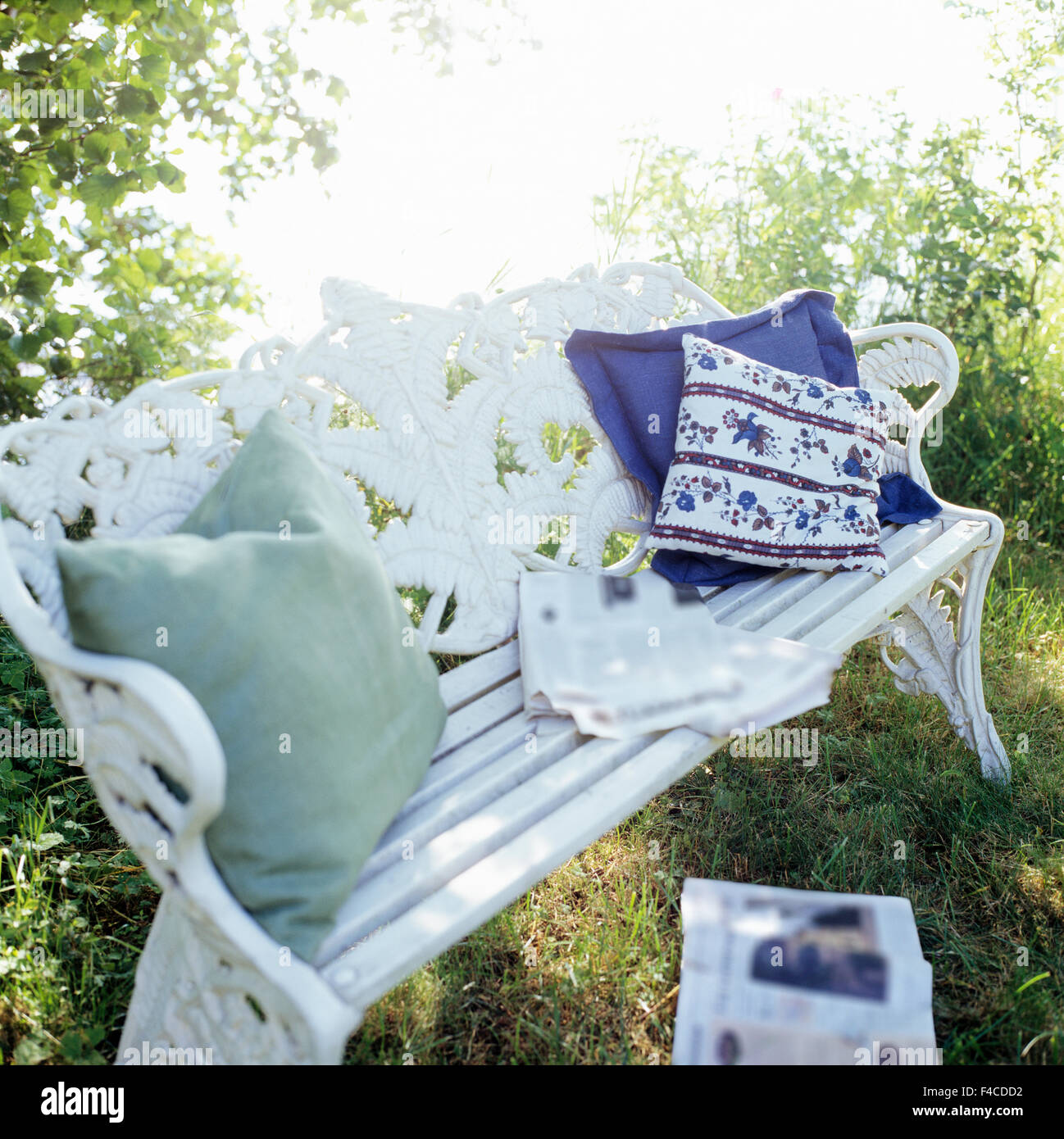 Cuscini e quotidiani su una panchina da giardino. Foto Stock