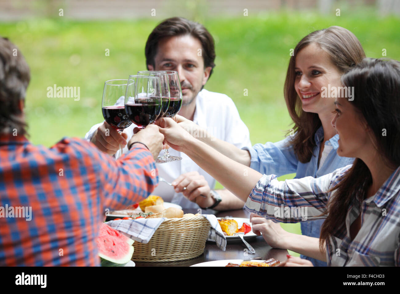 Amici clink bicchieri di vino rosso a cena all'aperto Foto Stock