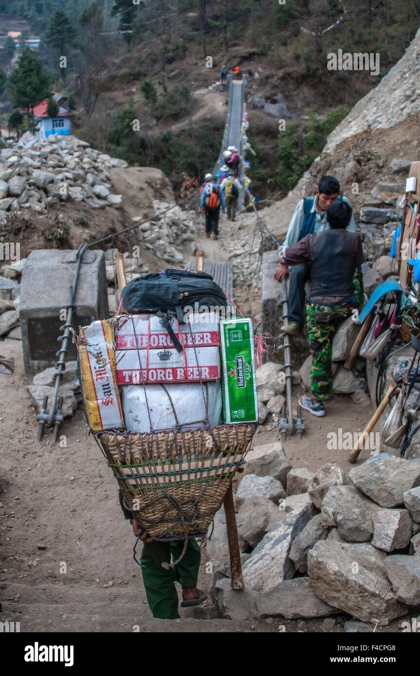 I portieri e il trekking attraversando ponte di sospensione, Nepal. Foto Stock