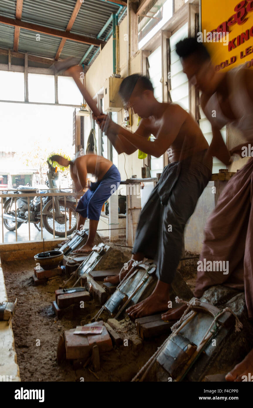 Giovane artigiano punzonatura di oro con un martello Foto Stock