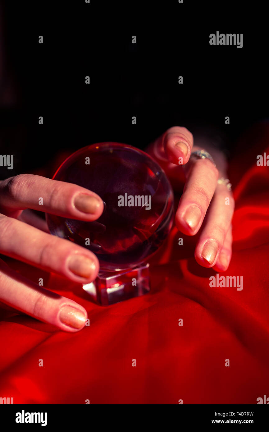 Mani tagliate di fortune teller utilizzando il rosso sfera di cristallo Foto Stock