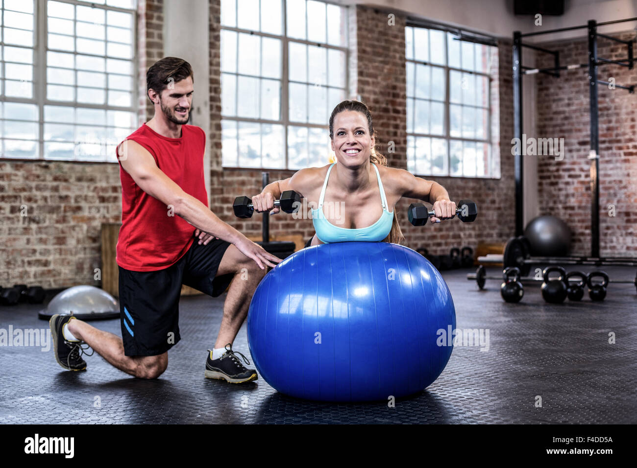 Personal trainer con il client il sollevamento pesi sulla palla ginnica Foto Stock
