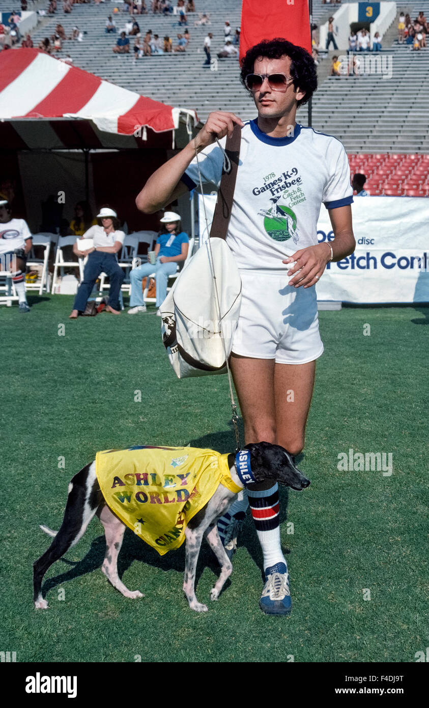 Il famoso disco-la cattura del cane Ashley Whippet prende al campo con il suo proprietario Alex Stein all annuale Frisbee cane World Championship tenutosi presso il Rose Bowl di Pasadena, California, Stati Uniti d'America. L'atletica cane potrebbe correre veloce come 35 miglia all'ora (56 km/h) e leap alta come 9 piedi (2,74 metri) per catturare i dischi volanti nella sua bocca. Ashley ha vinto i primi tre campionati del mondo che ha iniziato nel 1975, e un decennio più tardi il concorso è stato rinominato il Ashley Whippet Invitational in suo onore. Prima che egli morì nel 1985 all'età di 14, il cane eseguito anche nel Super Bowl e la Casa Bianca. Foto Stock