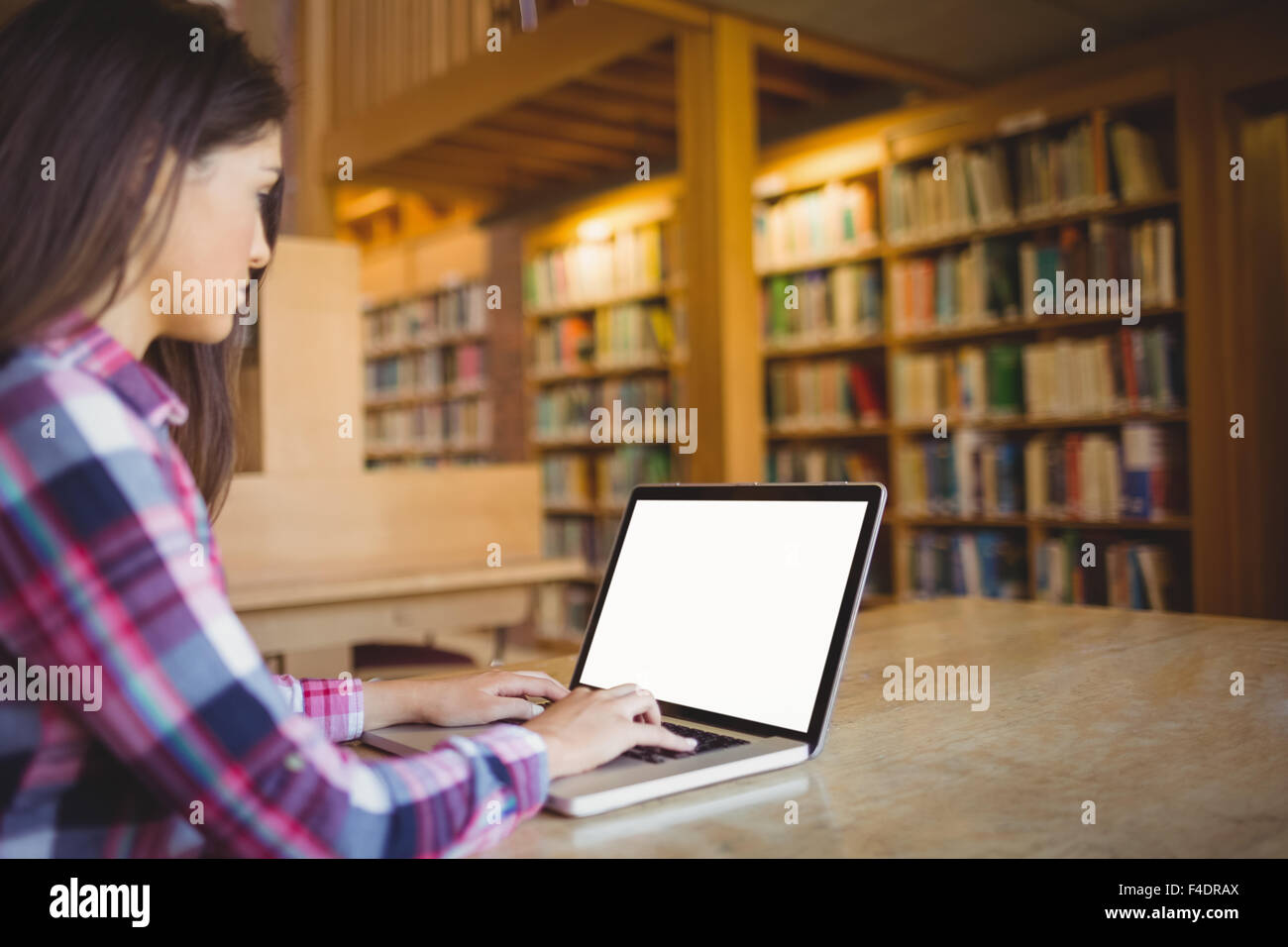 Studentessa utilizzando laptop in biblioteca Foto Stock