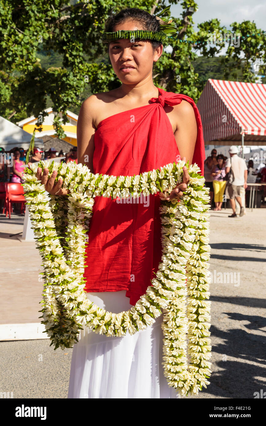 Oceano Pacifico, Polinesia francese Isole della Società, Huahine, tariffa. Donna in abito tradizionale azienda ilo per agli spettatori del festival. Foto Stock