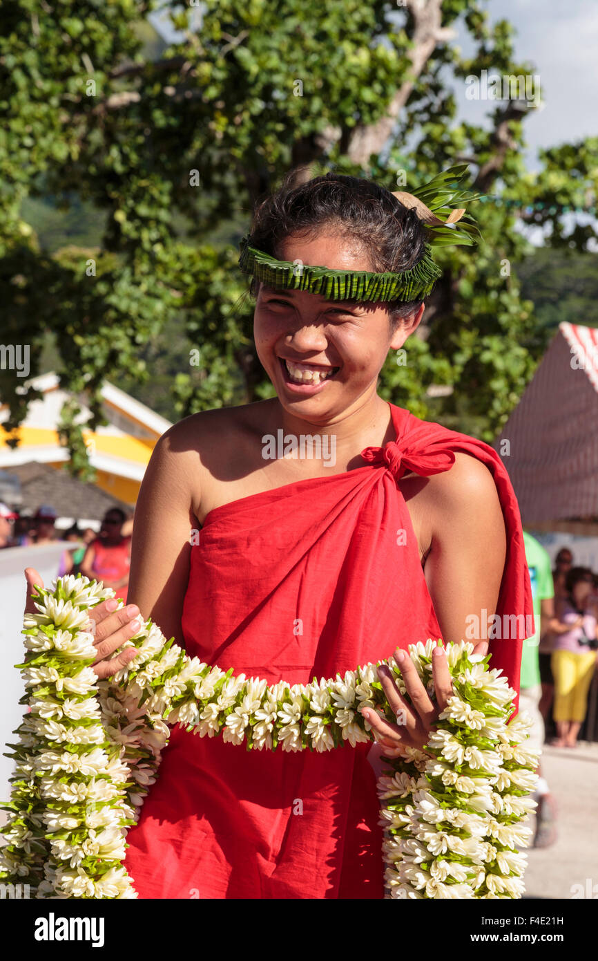 Oceano Pacifico, Polinesia francese Isole della Società, Huahine, tariffa. Donna in abito tradizionale azienda ilo per agli spettatori del festival. Foto Stock