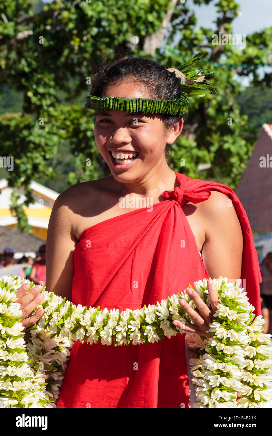 Oceano Pacifico, Polinesia francese Isole della Società, Huahine, tariffa. Donna in abito tradizionale azienda ilo per agli spettatori del festival. Foto Stock
