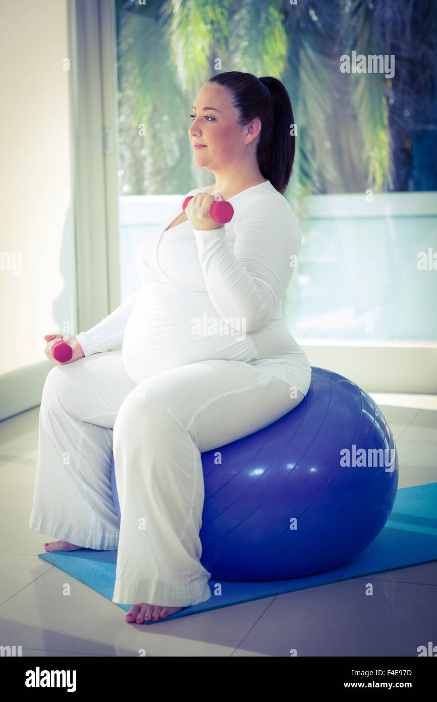 Donna incinta che esercitano con sfera Foto Stock