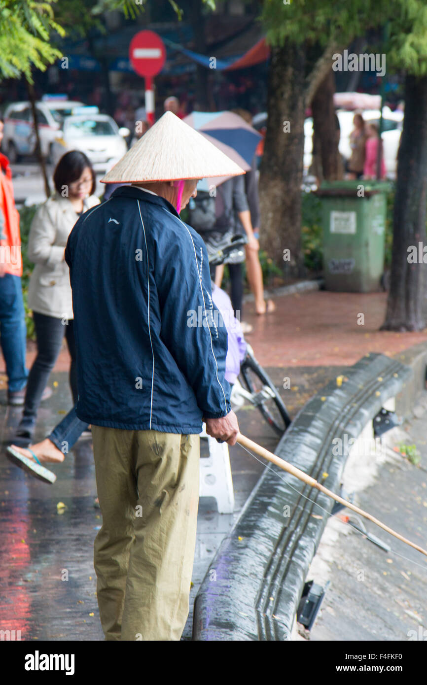 Uomo vietnamita la pesca sulla riva del Lago Hoan Kiem in Hanoi city center,città capitale,Vietnam Foto Stock