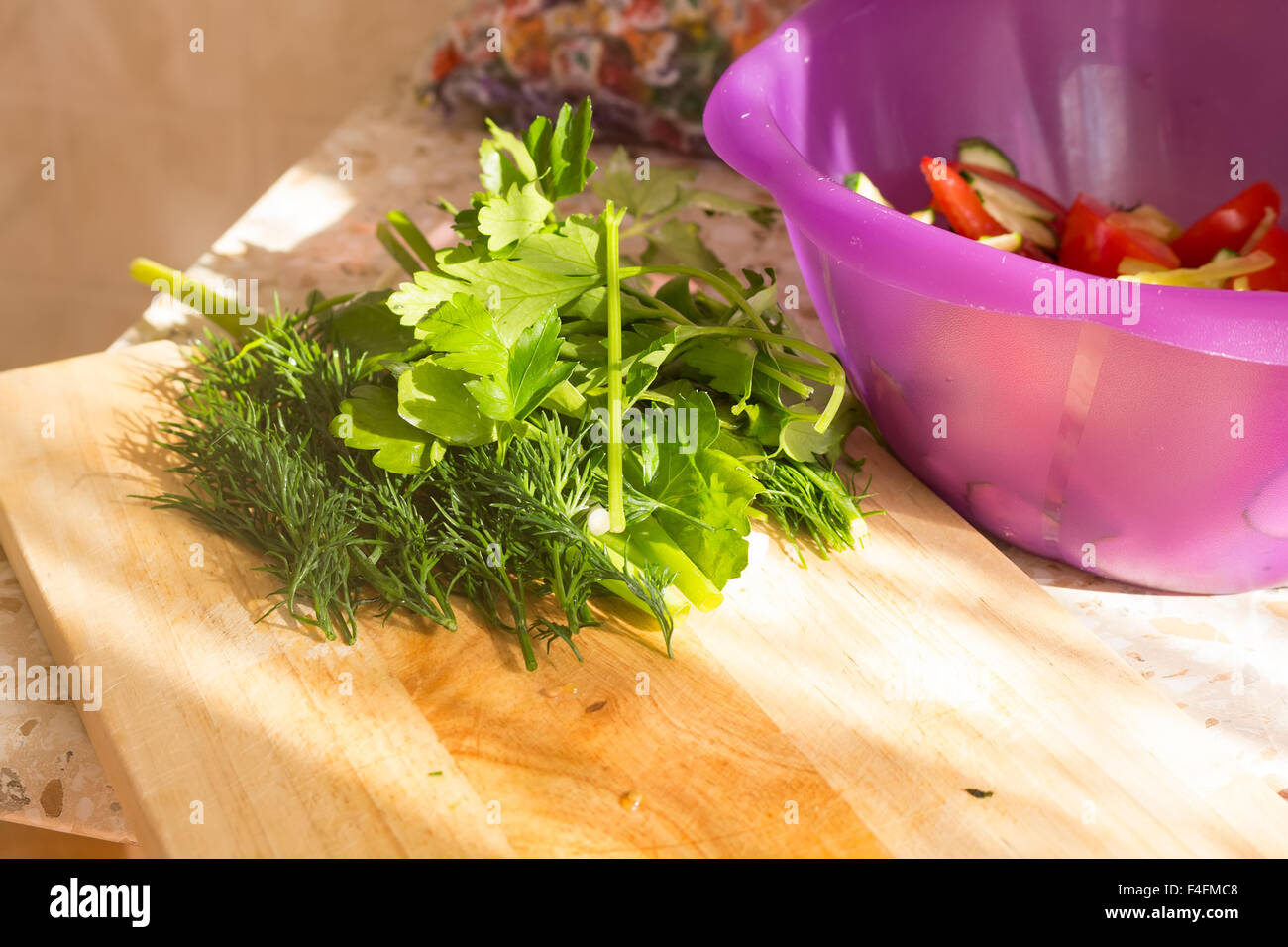 Il prezzemolo e l'aneto sul tagliere di legno. Preparazione di insalata di verdure e ortaggi freschi/insalata fresca con olio d'oliva Foto Stock