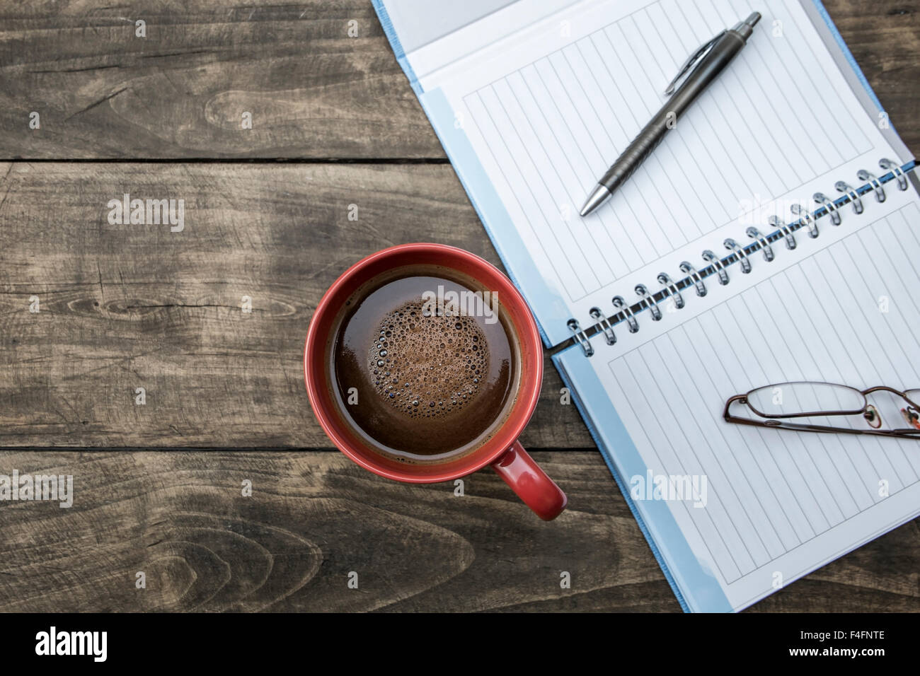 Penna per notebook e la tazza di caffè sul tavolo di legno dal di sopra Foto Stock