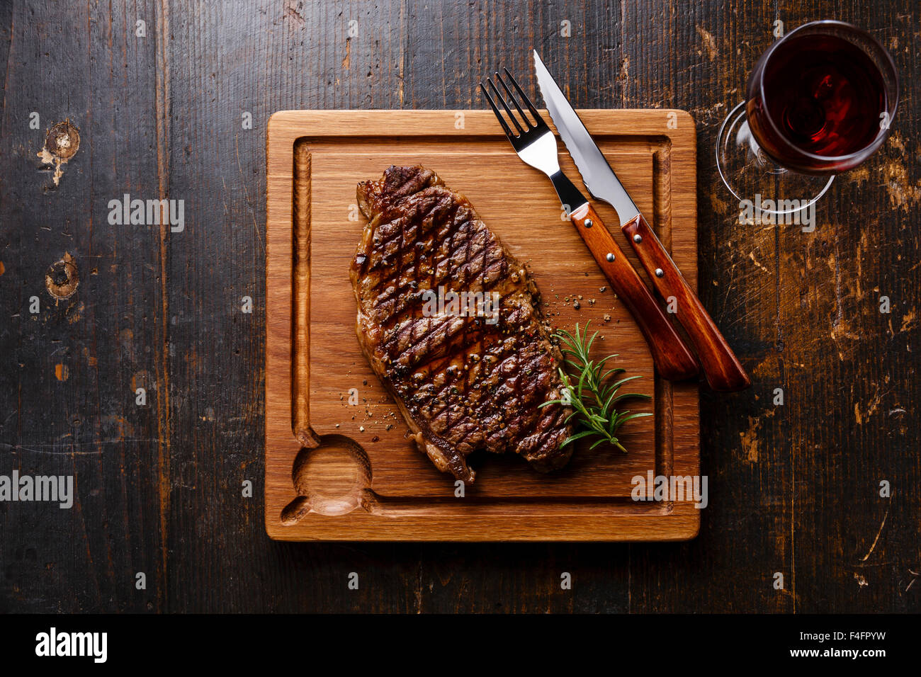 Bistecca alla griglia controfiletto e vino rosso sul tagliere in legno scuro dello sfondo Foto Stock