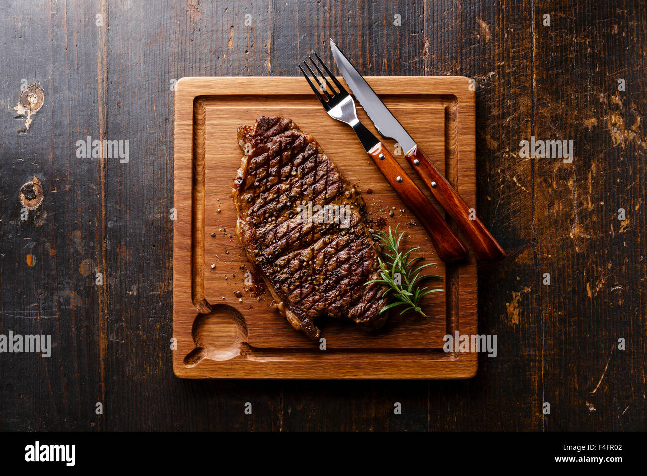 Bistecca alla griglia controfiletto di carne tagliere in legno scuro dello sfondo Foto Stock
