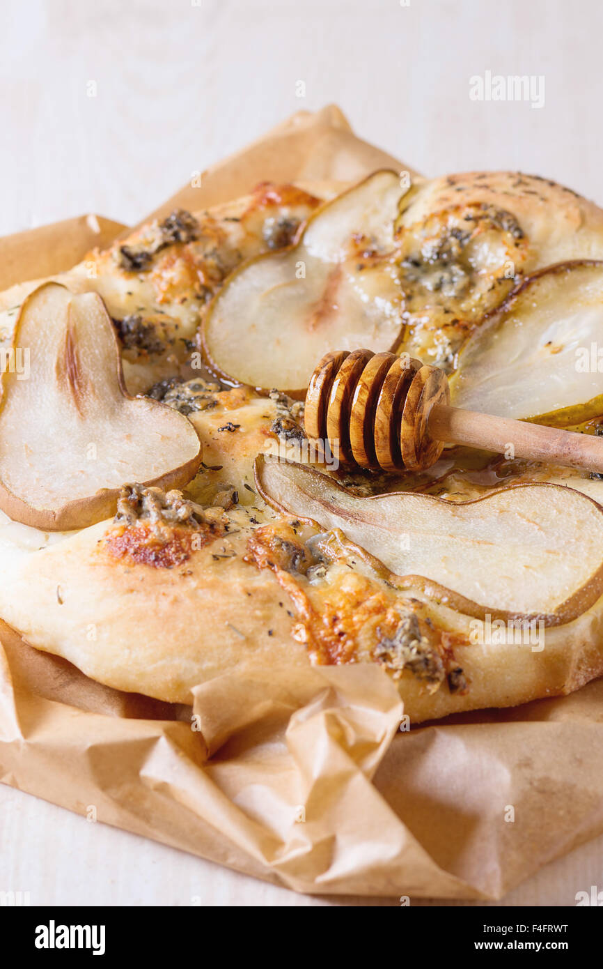 Tutta la pizza con pera, gorgonzola e miele con legno d'ulivo miele  bilanciere su carta da forno su bianco tavolo in legno Foto stock - Alamy