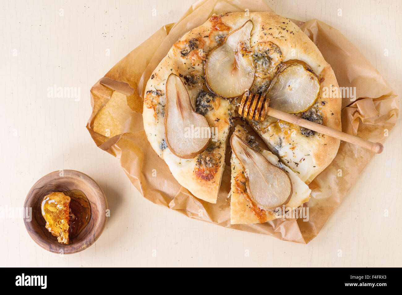 Fette di Pizza con pera, gorgonzola e nido come forma di cuore in legno d'ulivo miele bilanciere su carta da forno su legno bianco t Foto Stock