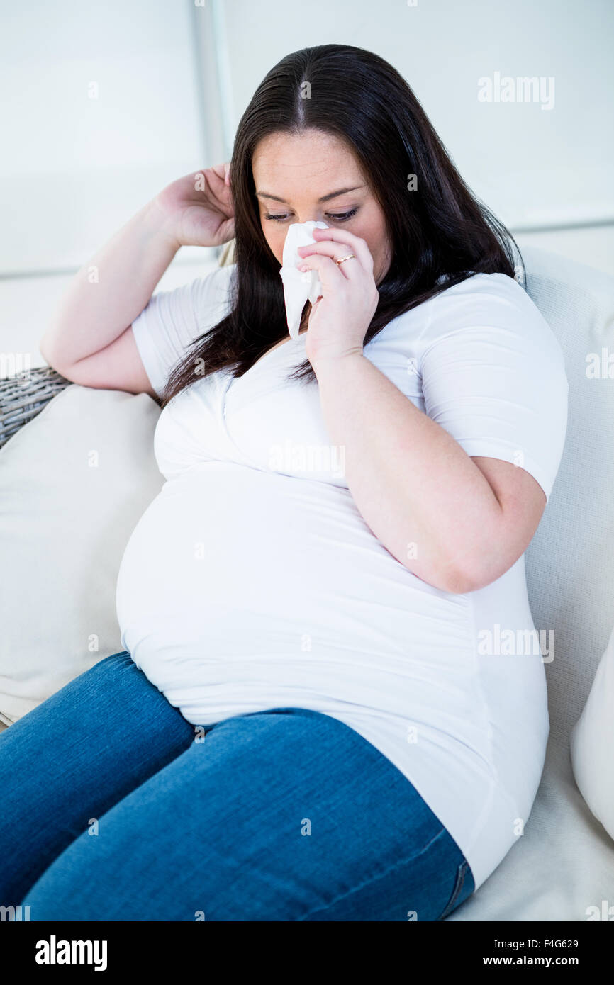 Donna incinta soffia il naso Foto Stock