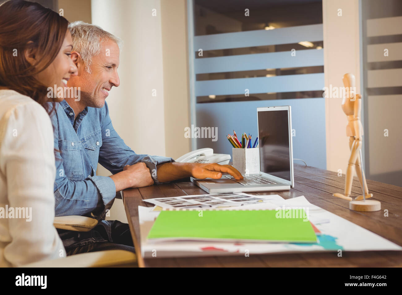 Happy business persone cercano in laptop in ufficio Foto Stock