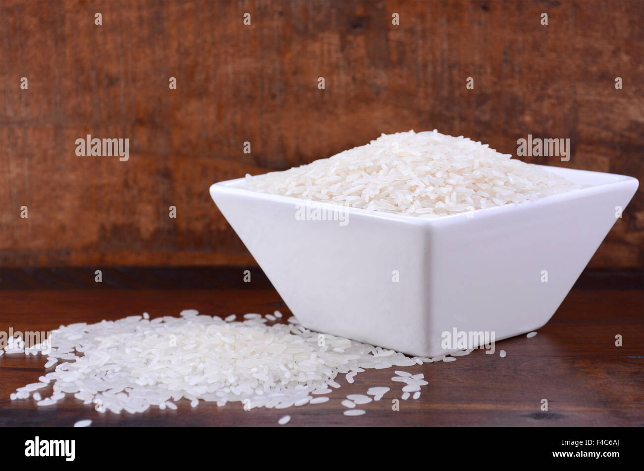 Square ciotola di riso bianco crudo su legno scuro dello sfondo vintage. Foto Stock