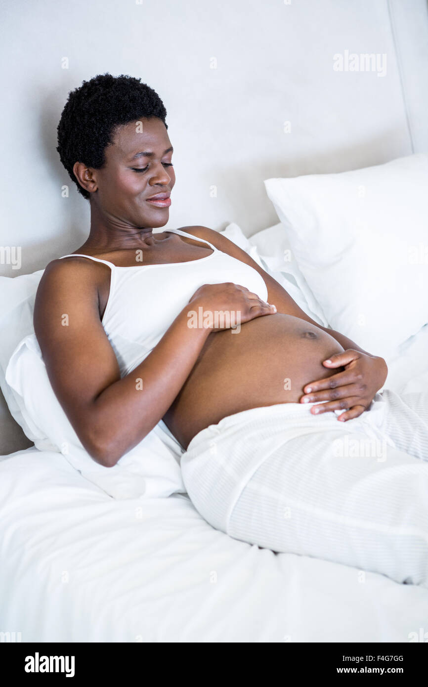 Donna incinta seduta nel letto Foto Stock