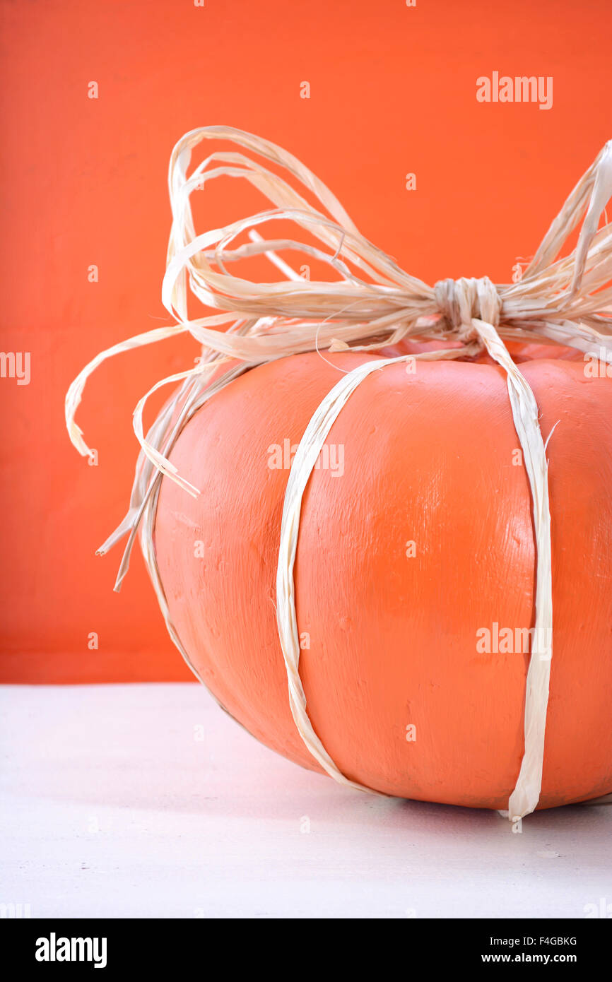 Moderno dipinto di zucca centrotavola decorato con rafia e paglia in legno bianco e tavolo in legno di colore arancione sfondo per Thanksgivng Foto Stock
