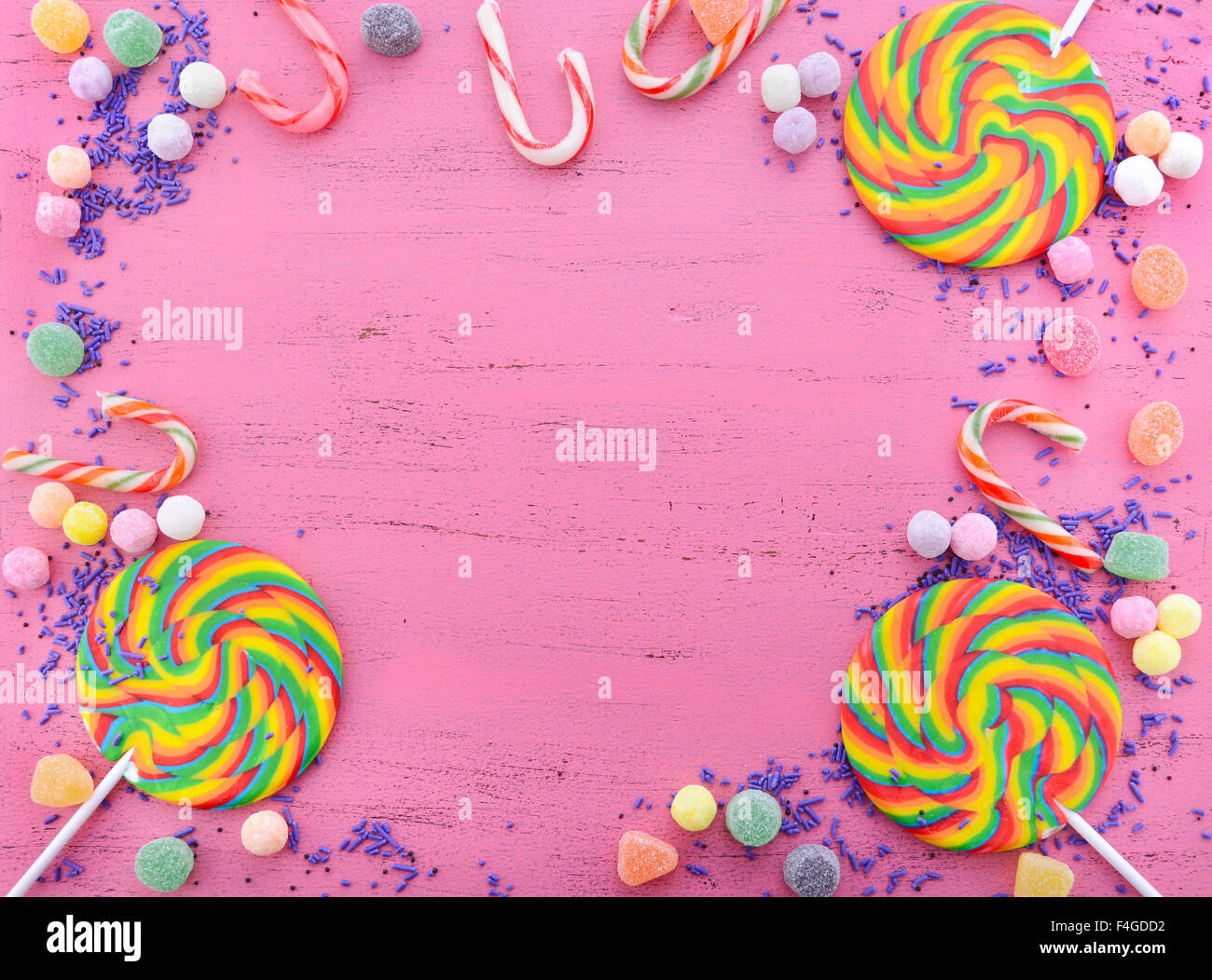 Caramelle assortite e rainbow lollipop su legno di rosa tavolo rustico sfondo con copia spazio. Foto Stock