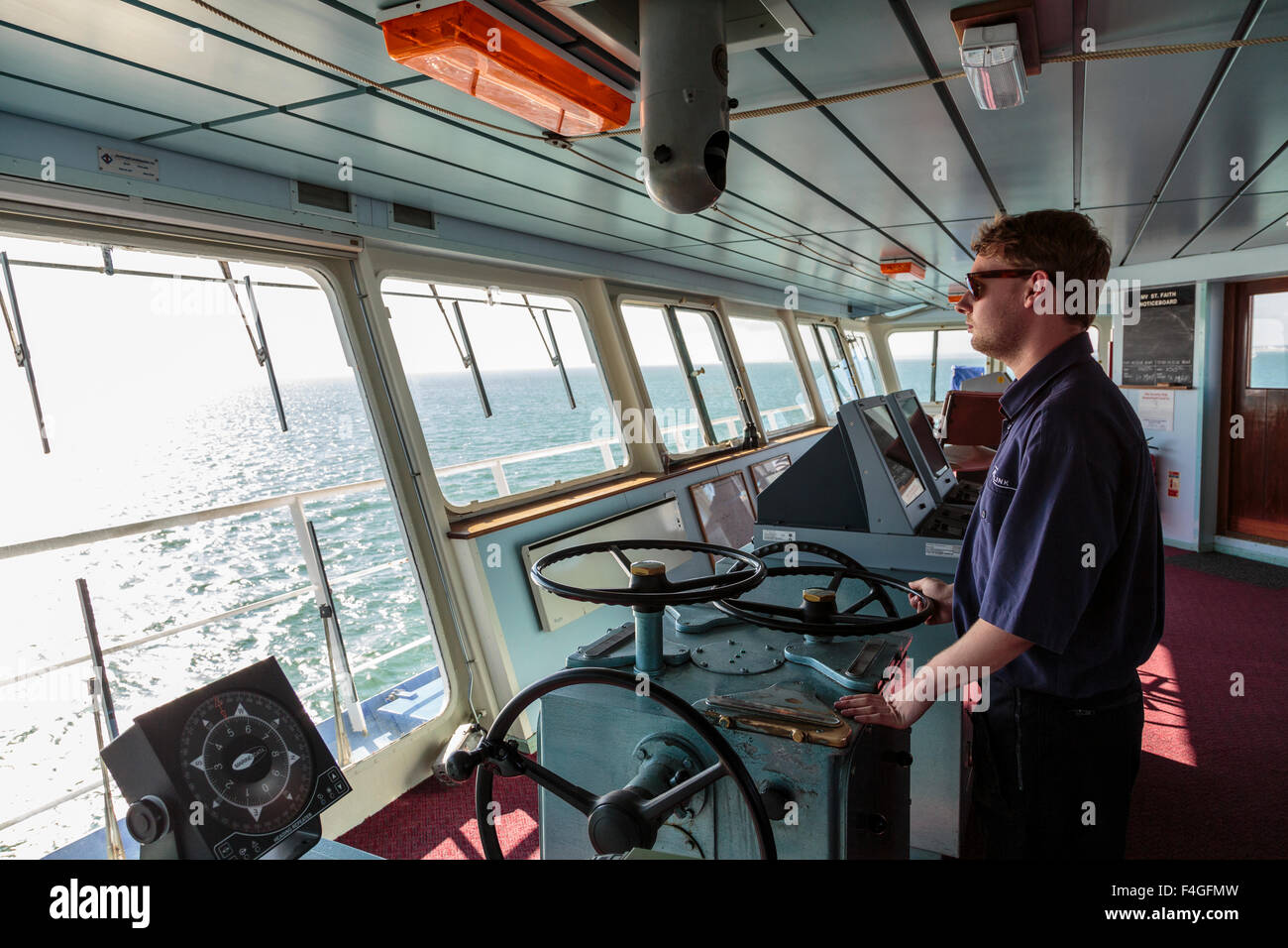 Un ufficiale al timone del ponte di una nave traghetto che attraversa il Solent tra Portsmouth e l'Isola di Wight, England Regno Unito Foto Stock