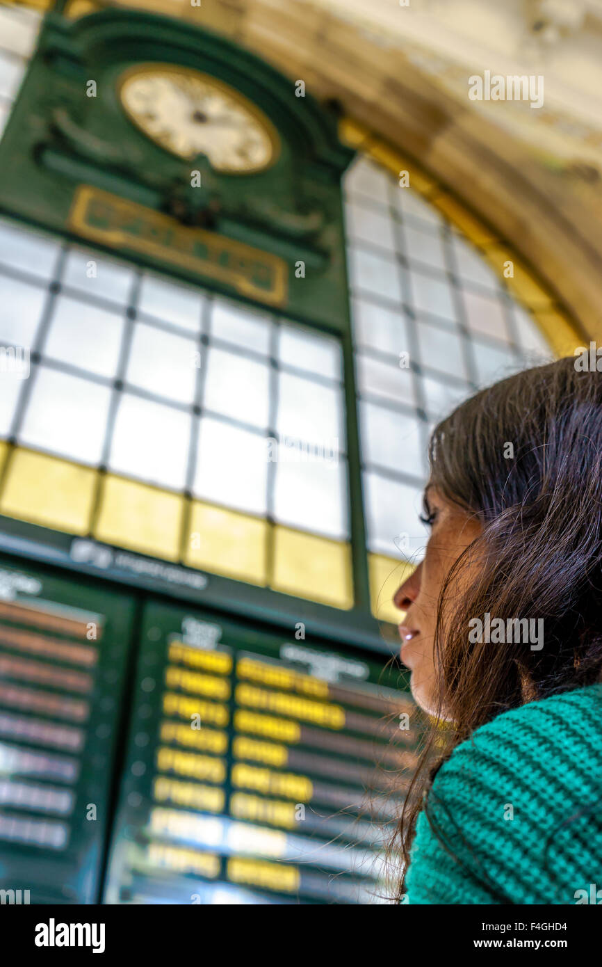 La donna legge l'orario dei treni in alla stazione ferroviaria di Sao Bento. Ottobre, 2015. Porto, Portogallo. Foto Stock