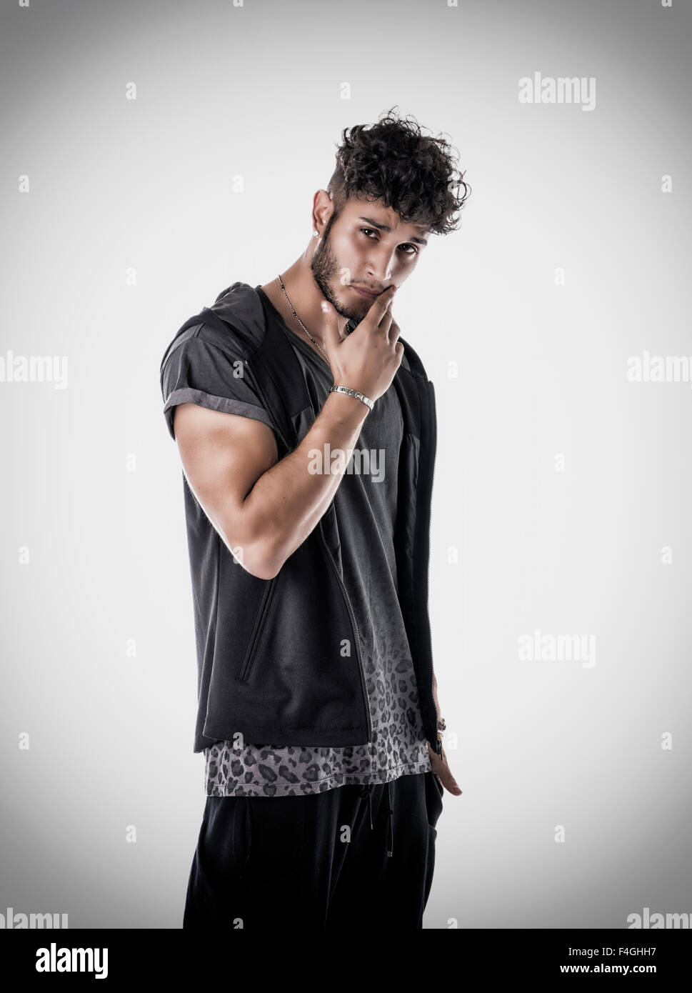 Bello duro giovane uomo in scuro incappucciati t-shirt su sfondo chiaro, guardando la fotocamera Foto Stock