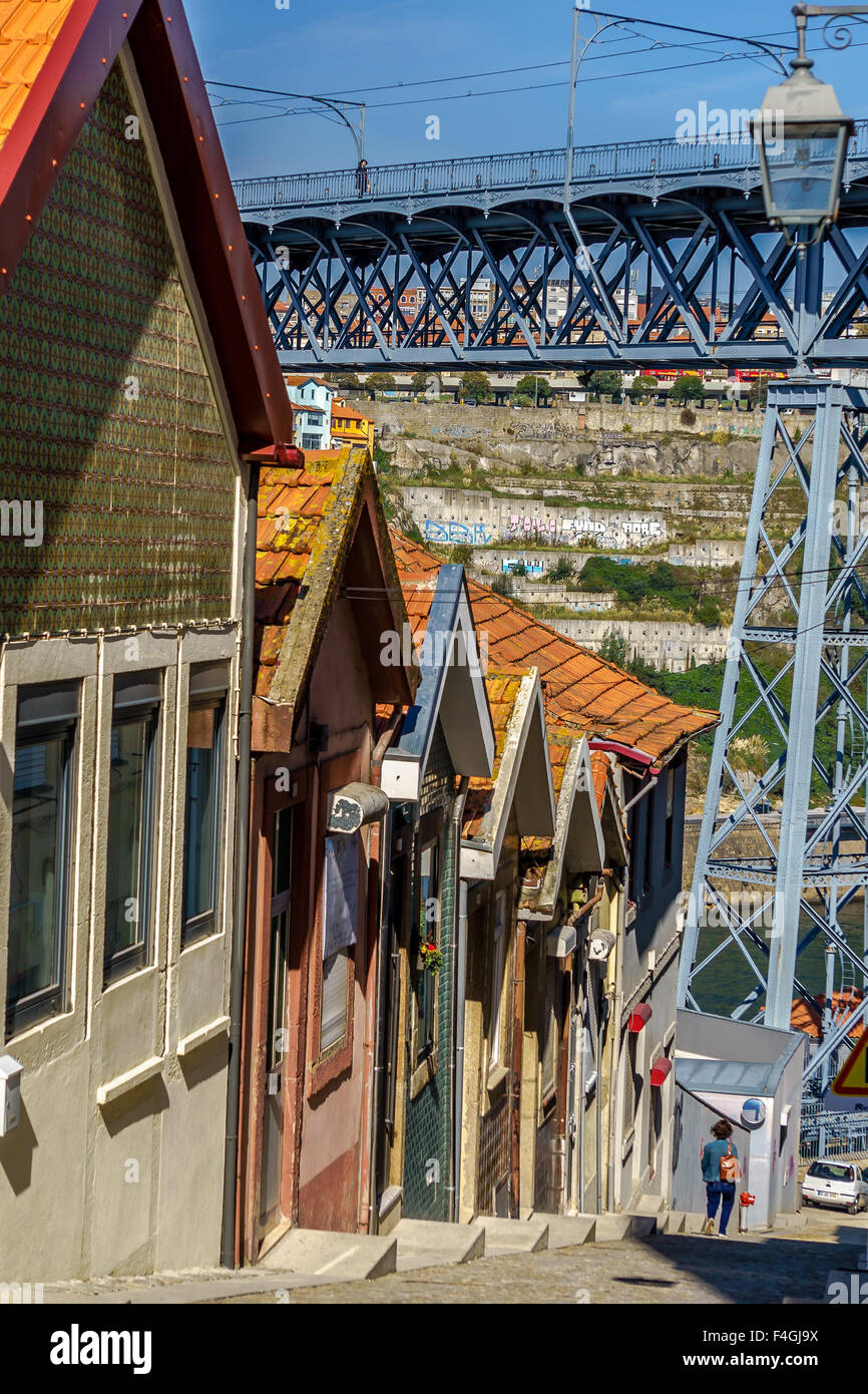 Una persona che cammina davanti ad una fila di case verso il Ponte Luis i bridge in Gaia. Ottobre, 2015. Porto, Portogallo. Foto Stock
