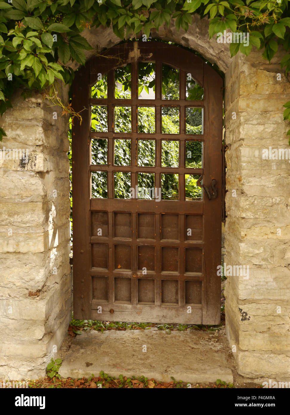 Un cancello di legno in un muro di pietra con il fogliame intorno all'entrata, a Tallinn in Estonia Foto Stock