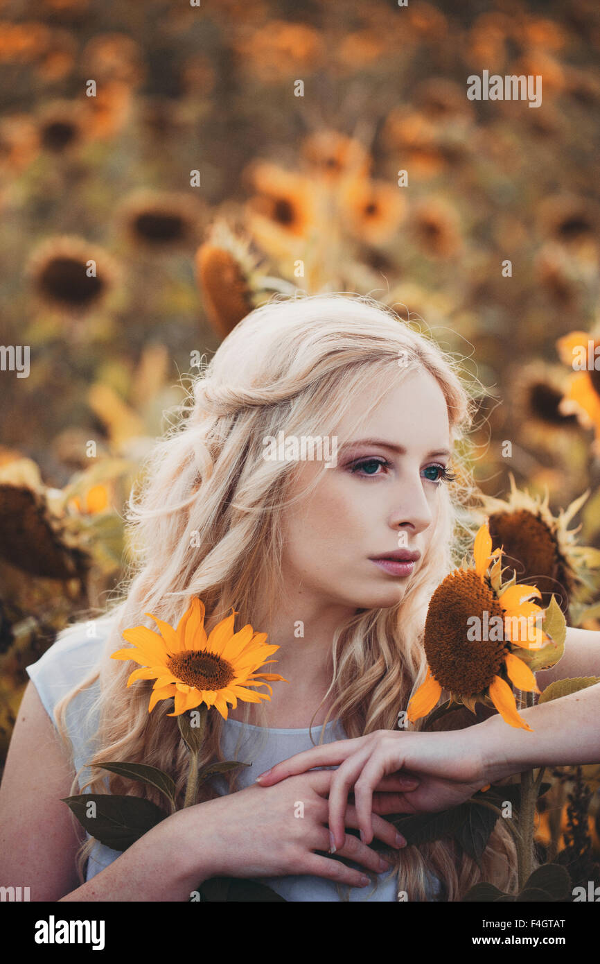 Bella donna bionda in un campo di girasoli Foto Stock