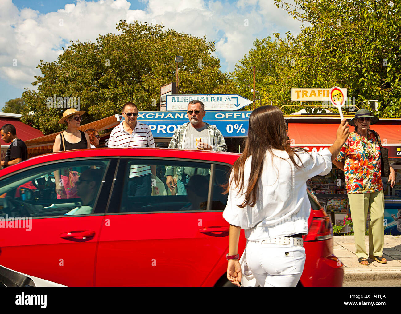 Trogir, Croazia - poliziotta conduce il traffico automobilistico a crosswalk pedonale vicino le bancarelle del mercato Foto Stock