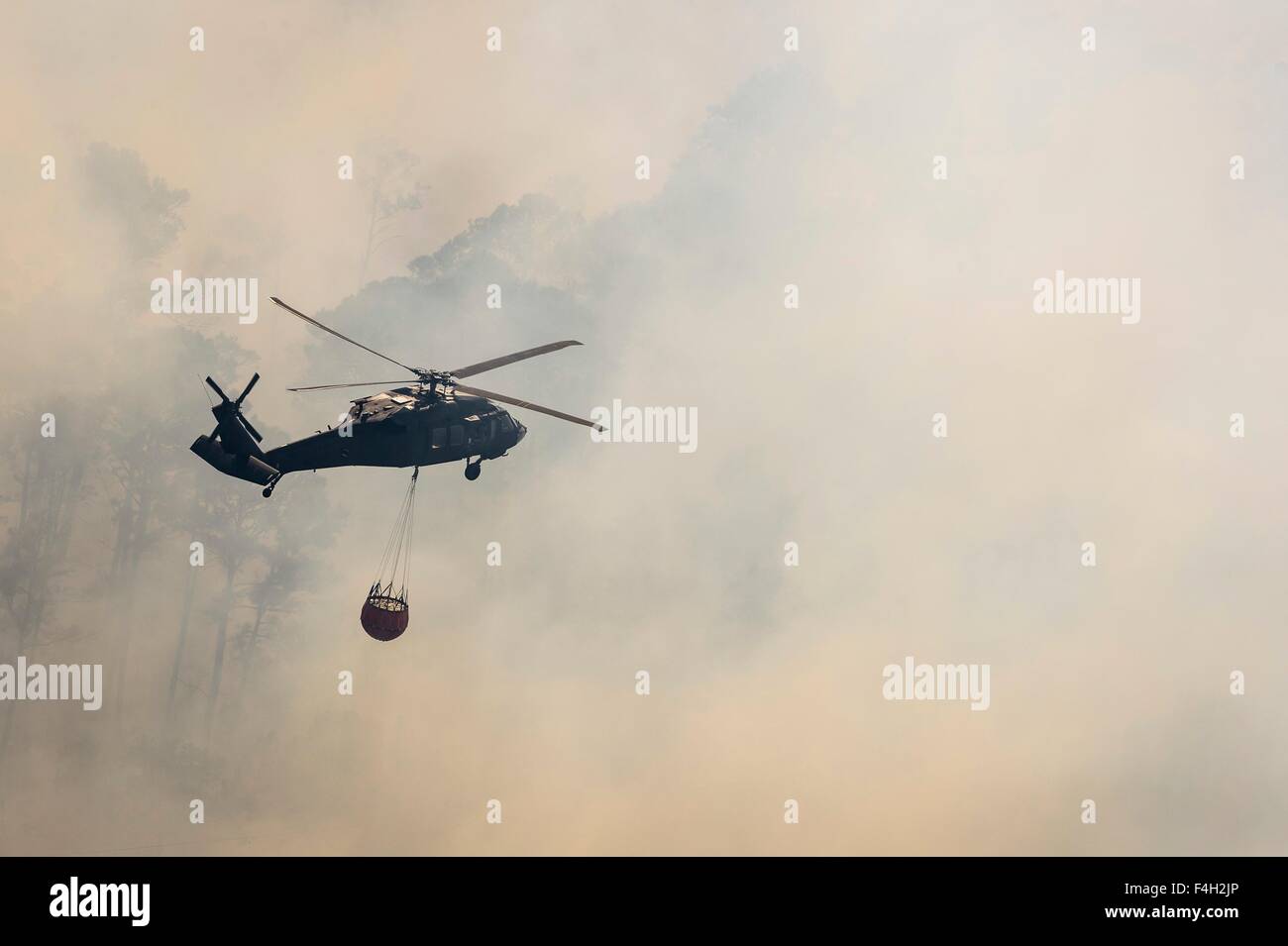 Un esercito di Texas National Guard UH-60 Black Hawk elicottero gocce acqua sui pini nascosto Fire Ottobre 14, 2015 vicino a Bastrop, Texas. Foto Stock