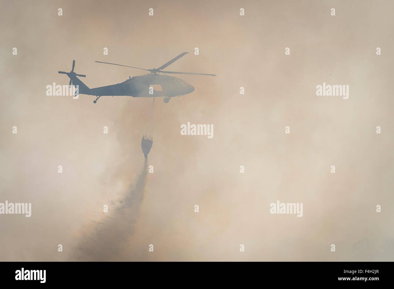 Un esercito di Texas National Guard UH-60 Black Hawk elicottero gocce acqua sui pini nascosto Fire Ottobre 14, 2015 vicino a Bastrop, Texas. Foto Stock