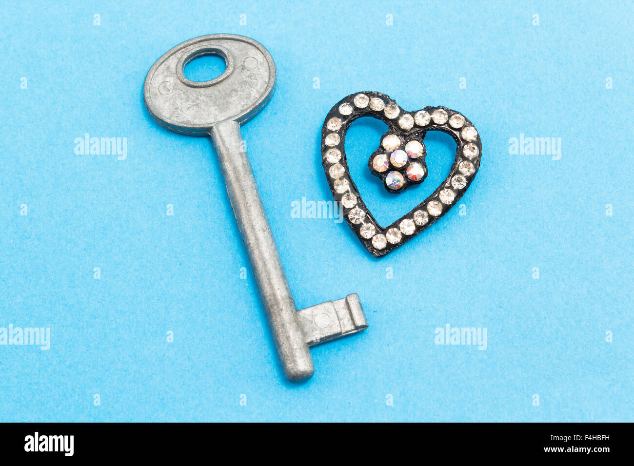 La chiave e il cuore di strass su uno sfondo blu. Foto Stock