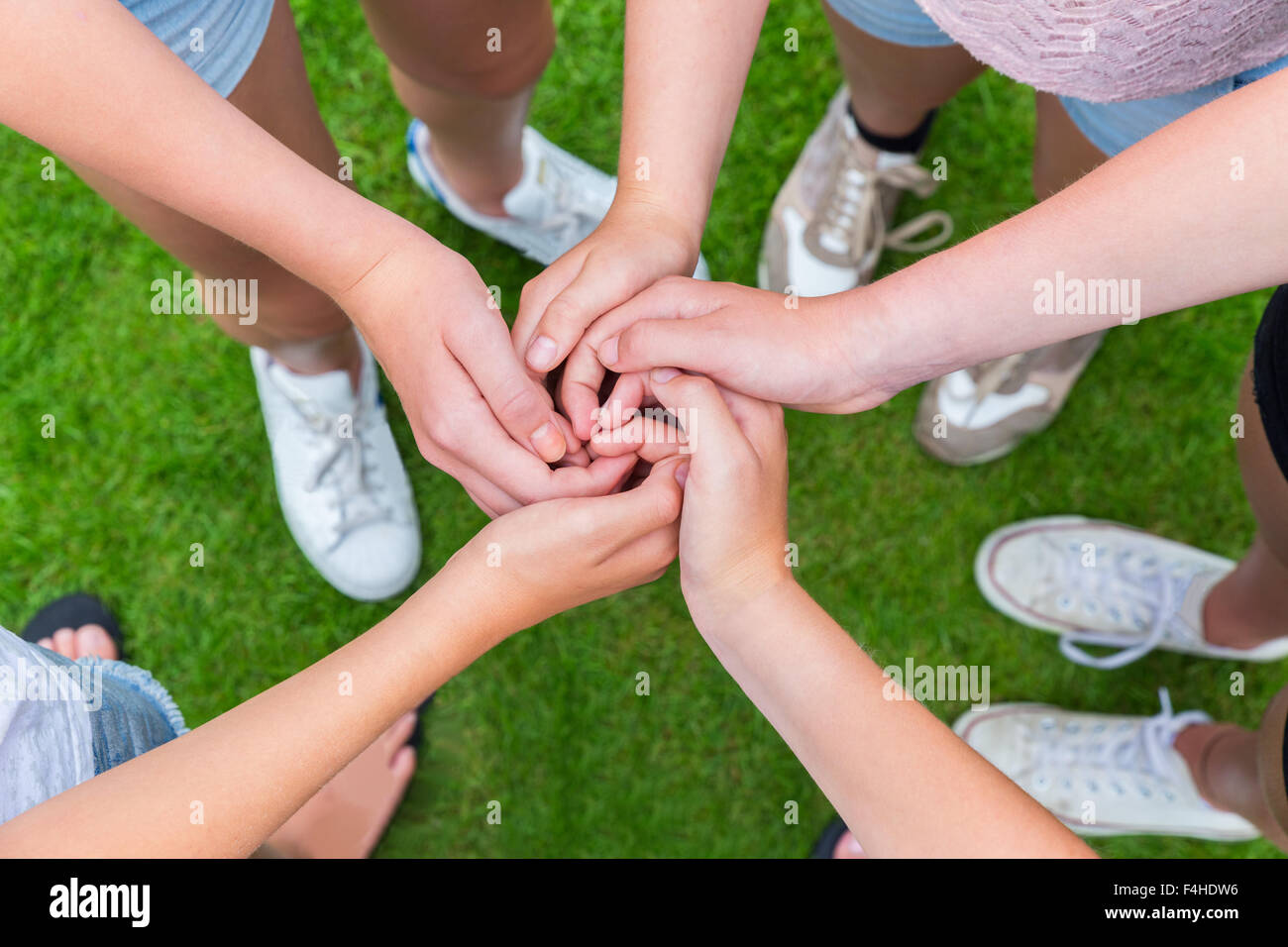 Cinque bracci con mani di giovani ragazze intrecciano sopra erba verde Foto Stock