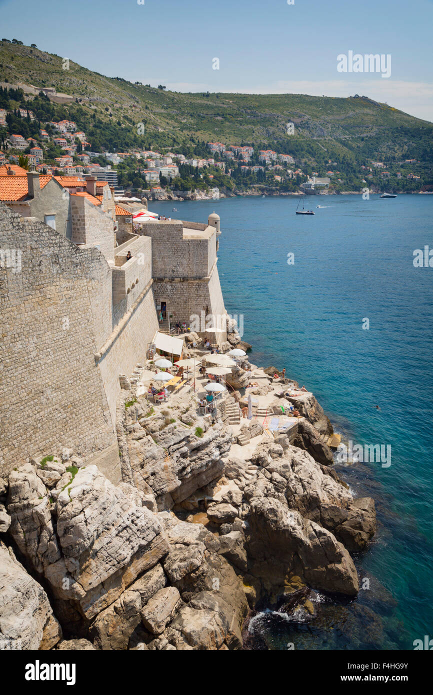 Dubrovnik, Dubrovnik-Neretva County, Croazia. Visitatori sulla passeggiata delle mura della città vecchia. Cafe sotto le mura. La città vecchia Foto Stock