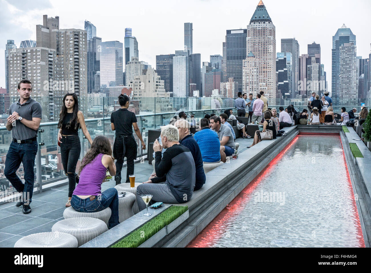 Folla di giovani si radunano intorno riflettendo piscina sulla terrazza dell'inchiostro 48 hotel bar sul tetto godendo bevande socializzare e vista sullo skyline Foto Stock