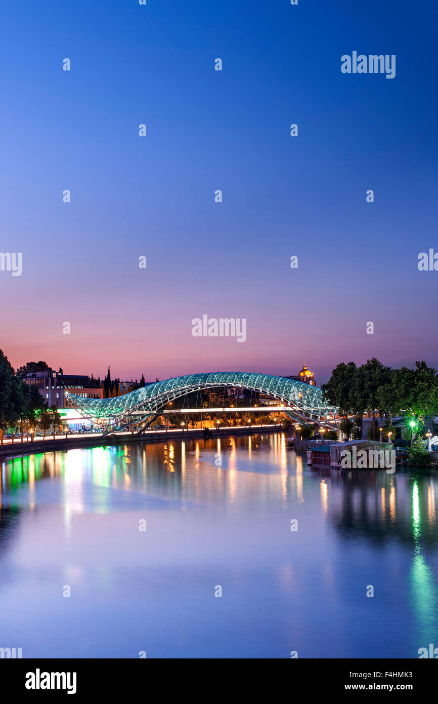Vista del tramonto del ponte di pace, un pedone ponte che attraversa il fiume Mtkvari a Tbilisi, capitale della Georgia. Foto Stock
