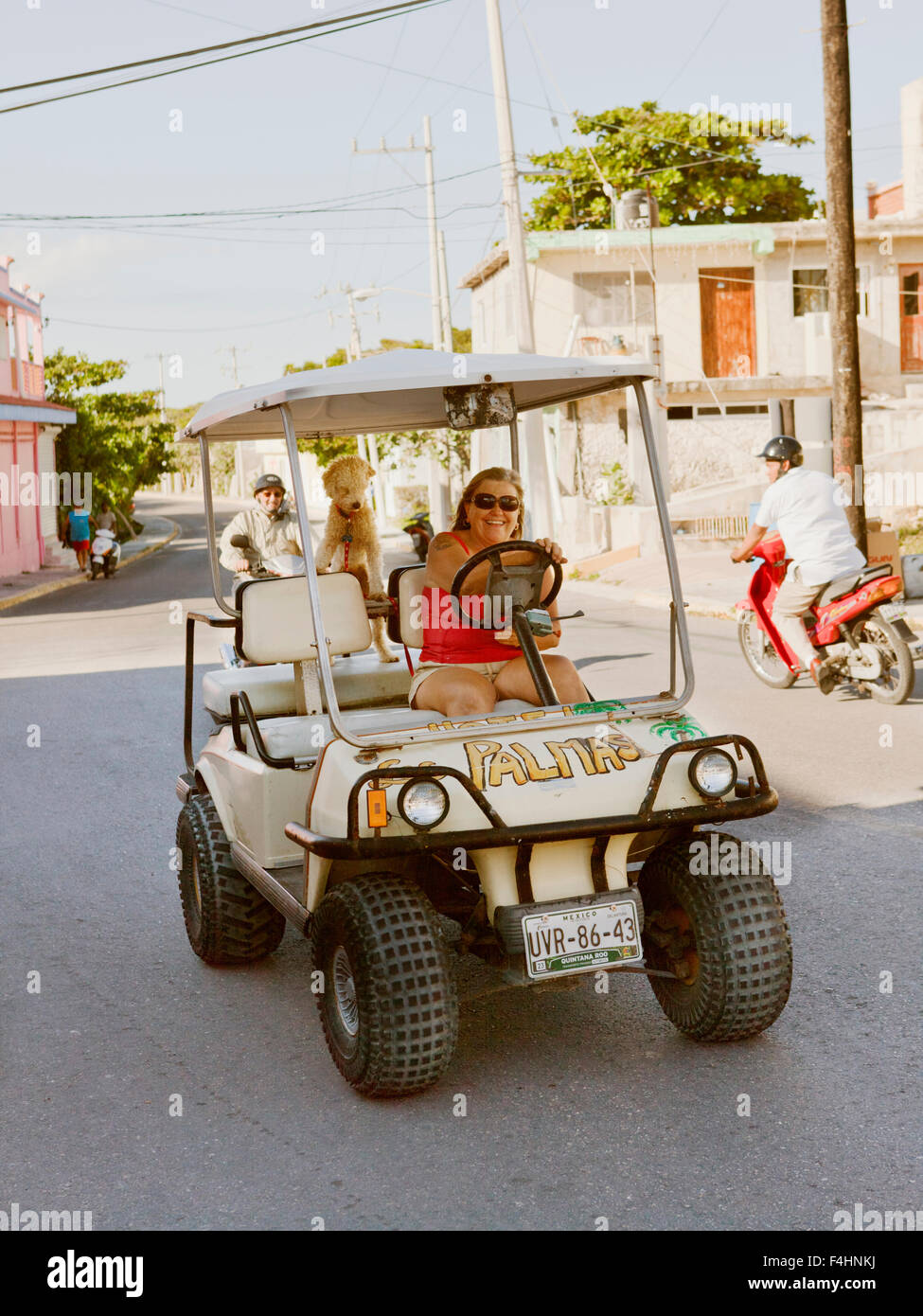 Un locale ex- pat la sua unità carrello da golf attraverso la città. IIsla Mujeres, Quintana Roo, Messico. Foto Stock
