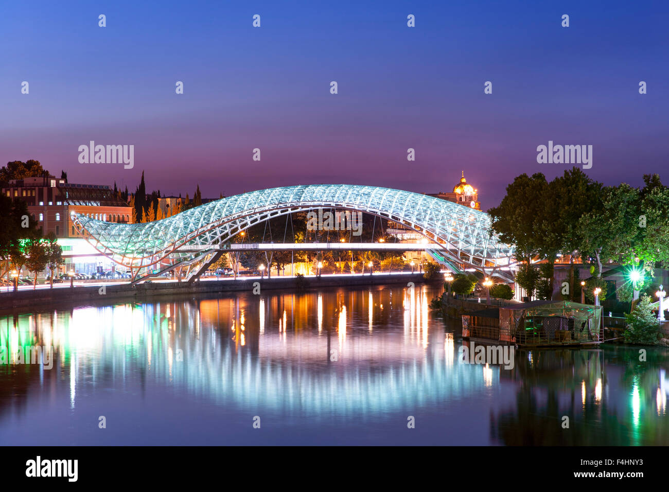 Vista del tramonto del ponte di pace, un pedone ponte che attraversa il fiume Mtkvari a Tbilisi, capitale della Georgia. Foto Stock