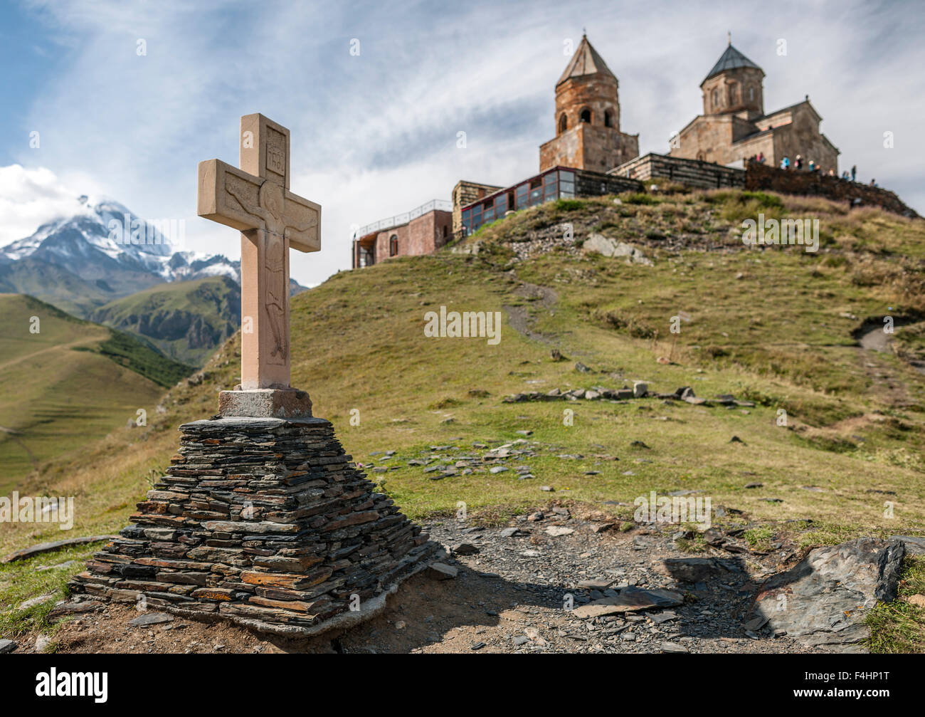 Croce e la Gergeti Trinity Church nelle montagne del Caucaso a nord della Georgia. Foto Stock