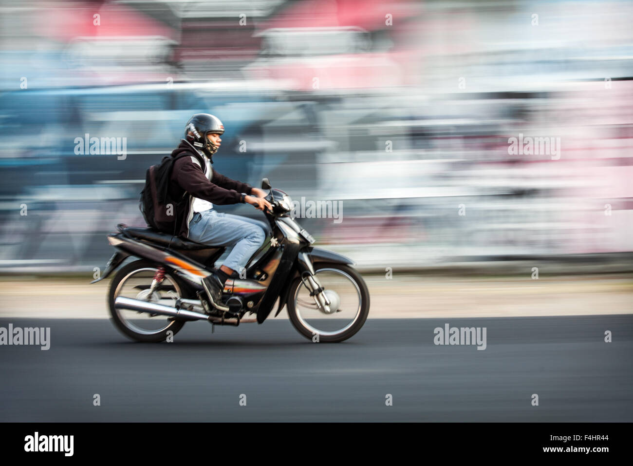 Il panning fotografia immagine del motociclista accelerando da una offuscata coperto di graffiti. parete effetti fotografici creati mediante panning e rallentare la velocità dello shutter Foto Stock