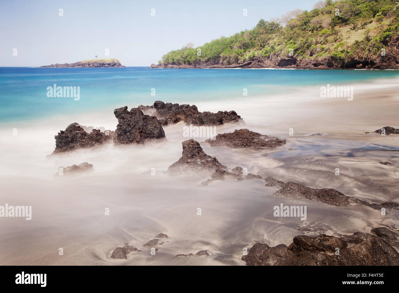 Scenic seascape e lunga esposizione foto di idilliaca spiaggia di Bali con il mare turchese colori e nebbioso acque di marea. Una bella destinazione di viaggio Foto Stock