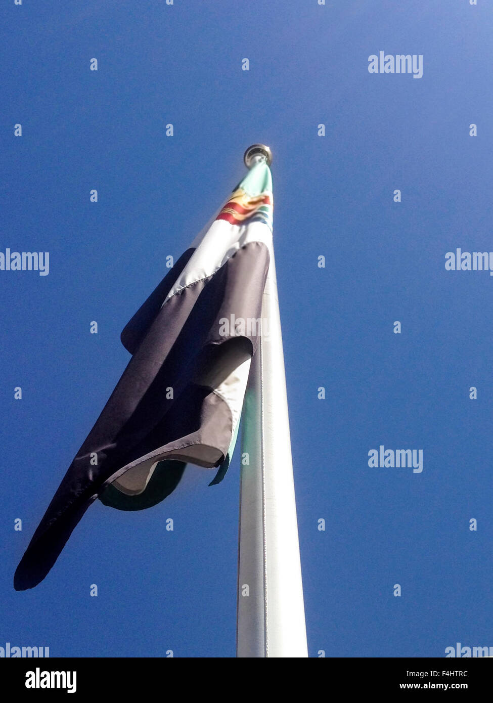 Regione dell'Extremadura bandiera sul pennone di una giornata soleggiata con cielo blu Foto Stock