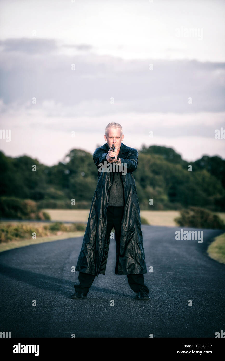 Un uomo con una pistola su una strada Foto Stock