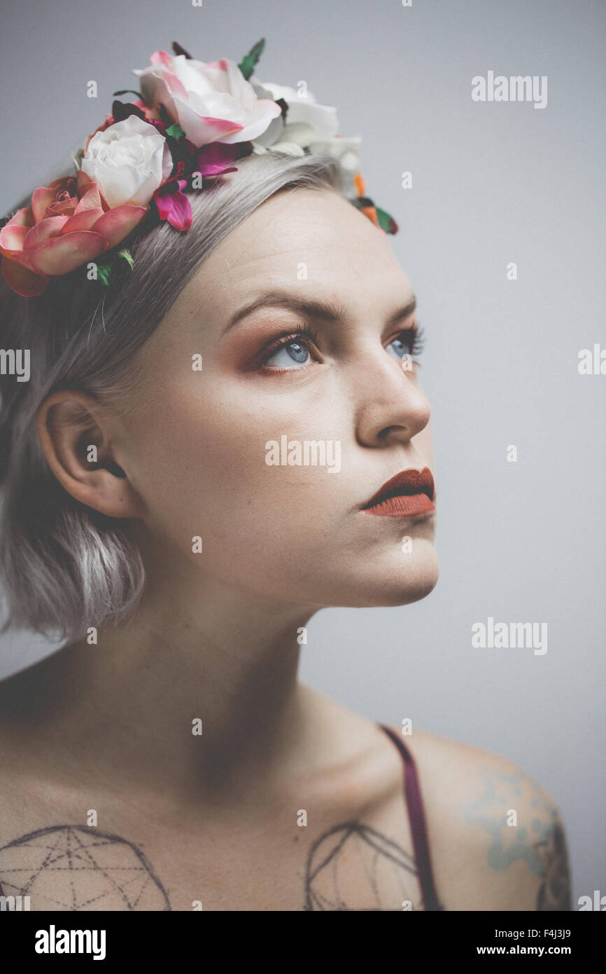 Giovane donna tatuata indossando una corona di fiori Foto Stock