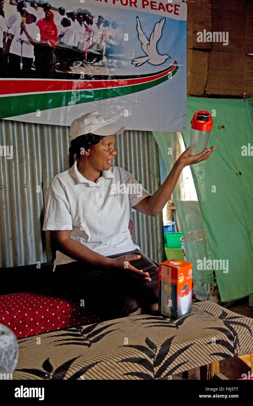Donna africana all'interno di casa buia tenendo a energia solare luce Kamere Lake Naivasha Kenya Foto Stock