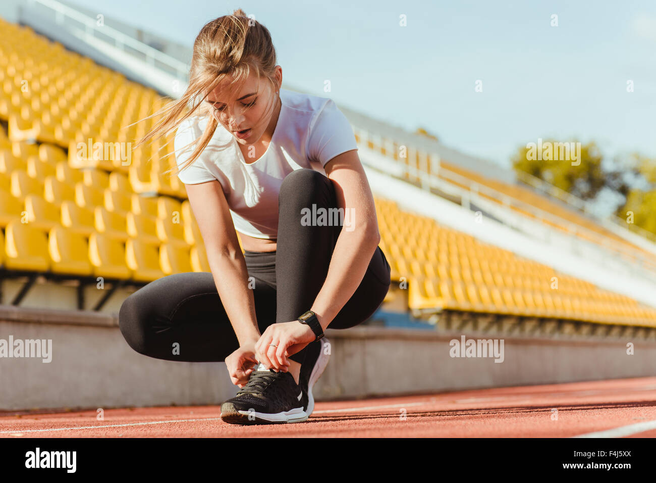 Ritratto di una donna fitness tie lacci delle scarpe a outdoor stadium Foto Stock